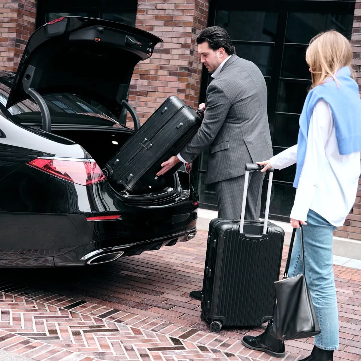 Professional chauffeur from Mosaik Motors helping a customer with luggage for an exclusive transfer service in Munich.