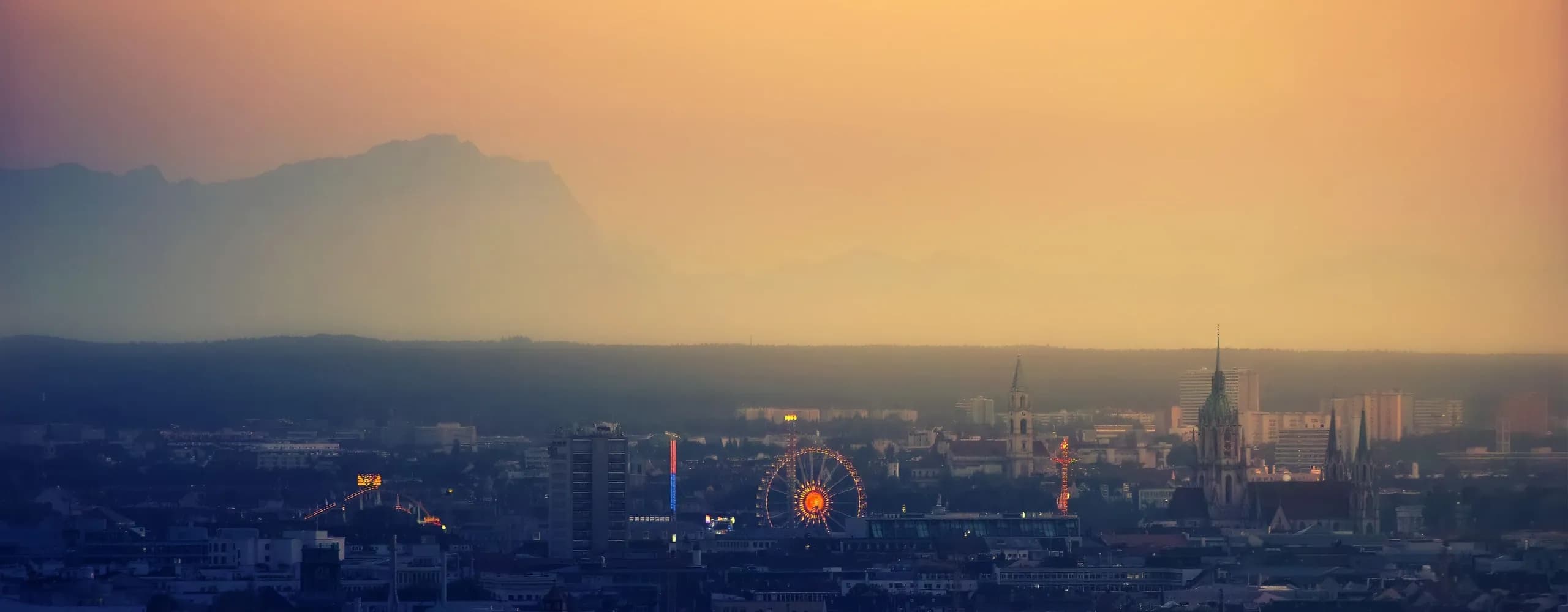 Exclusive chauffeur service Munich – Skyline and Oktoberfest Ferris wheel at dusk