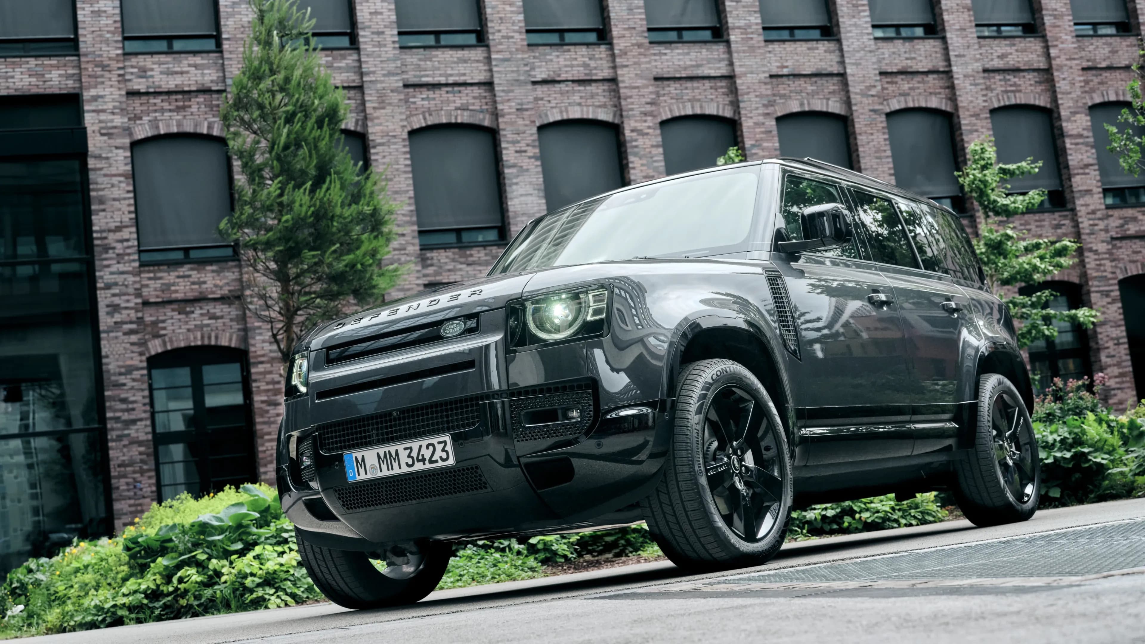 Grey Land Rover Defender 110 parked in front of a modern brick building at Design Offices Macherei in Munich