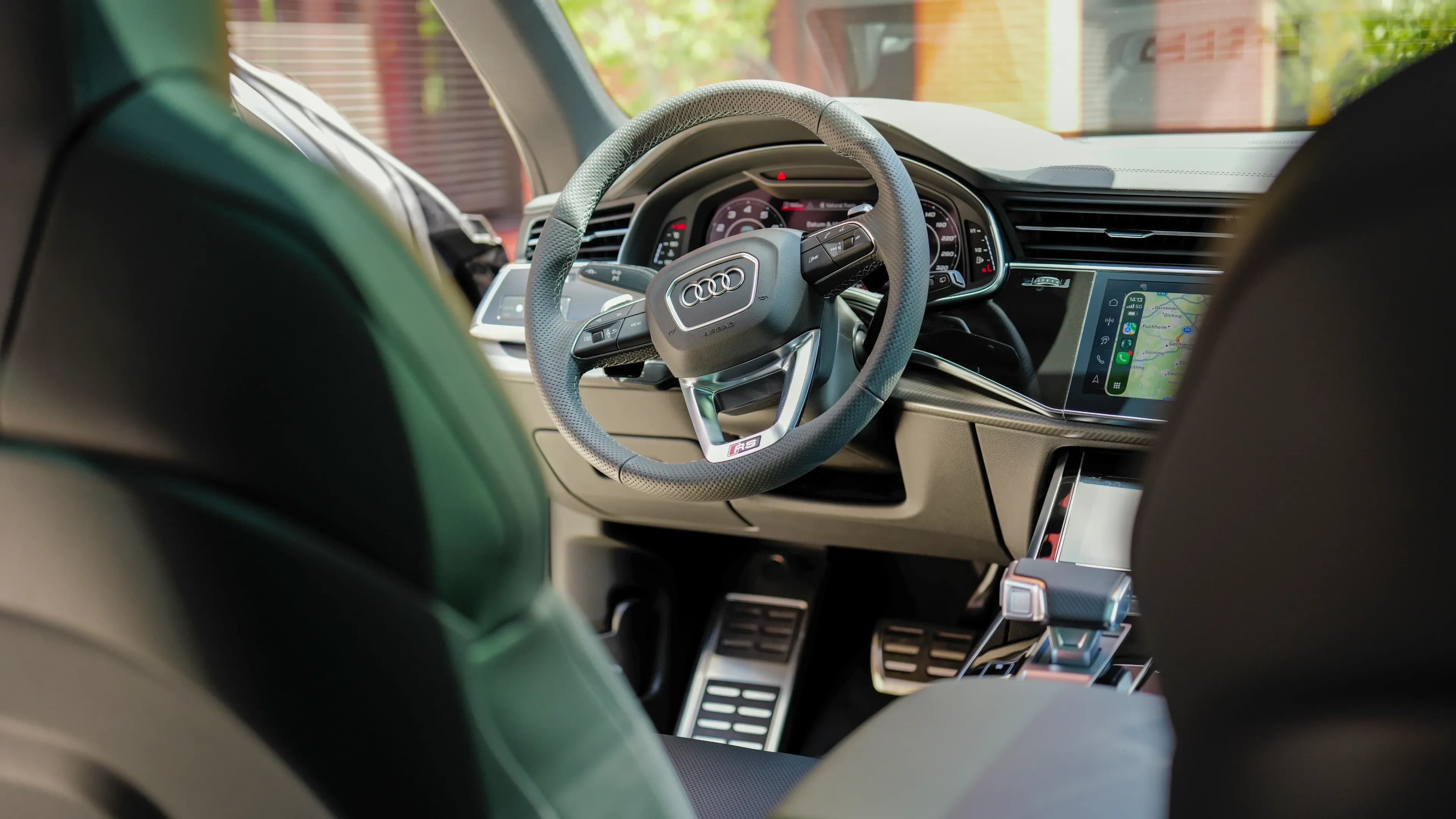 Großzügige Beinfreiheit und bequeme Fahrerposition am Sportlenkrad eines Audi RS Q8 der Luxusautovermietung Mosaik Motors in München.