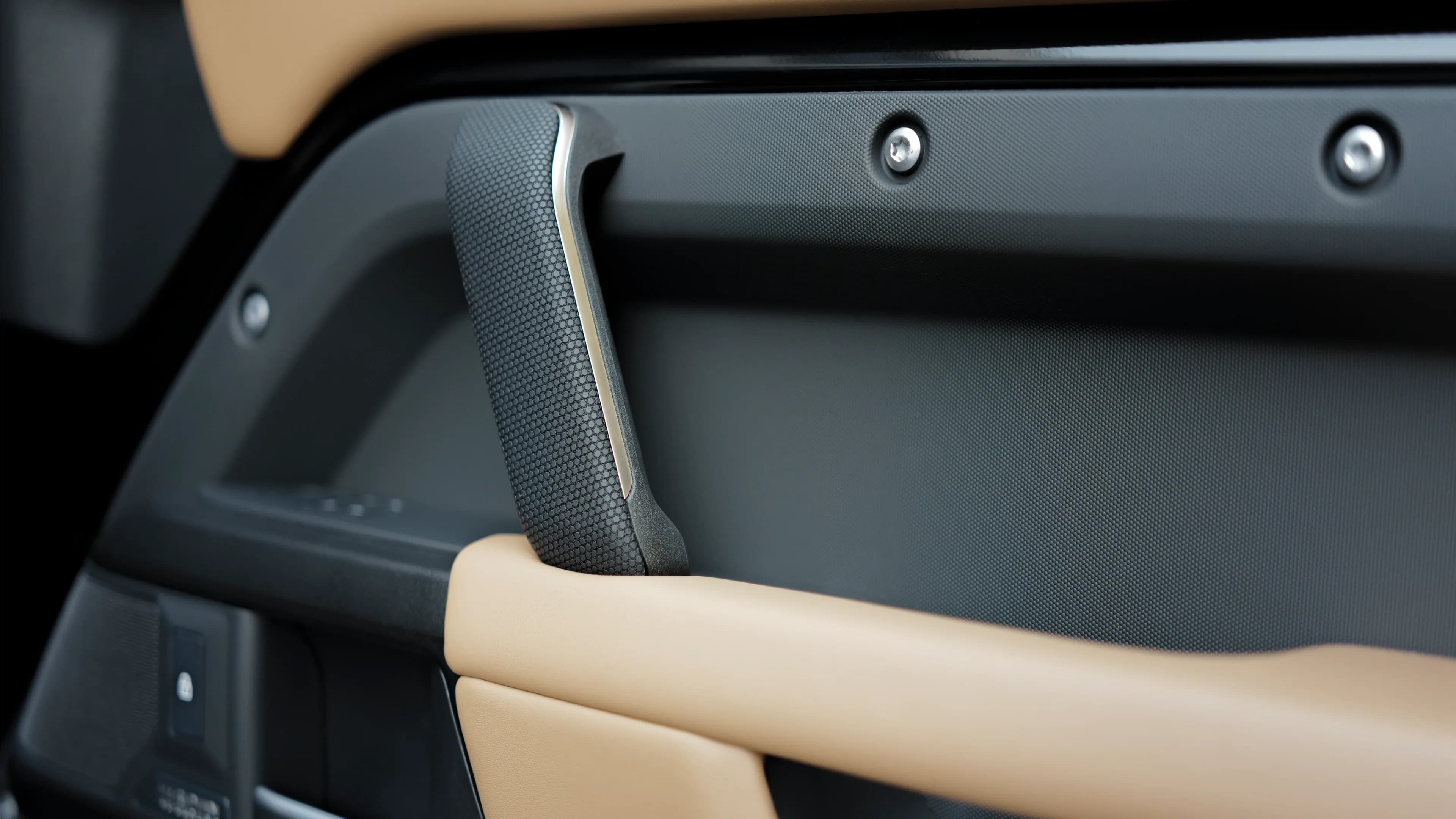 Land Rover Defender V8 mieten in München – Markante Cockpit-Griff-Details mit sichtbaren Schrauben im Interieur des Premium-Geländewagens von Mosaik Motors.