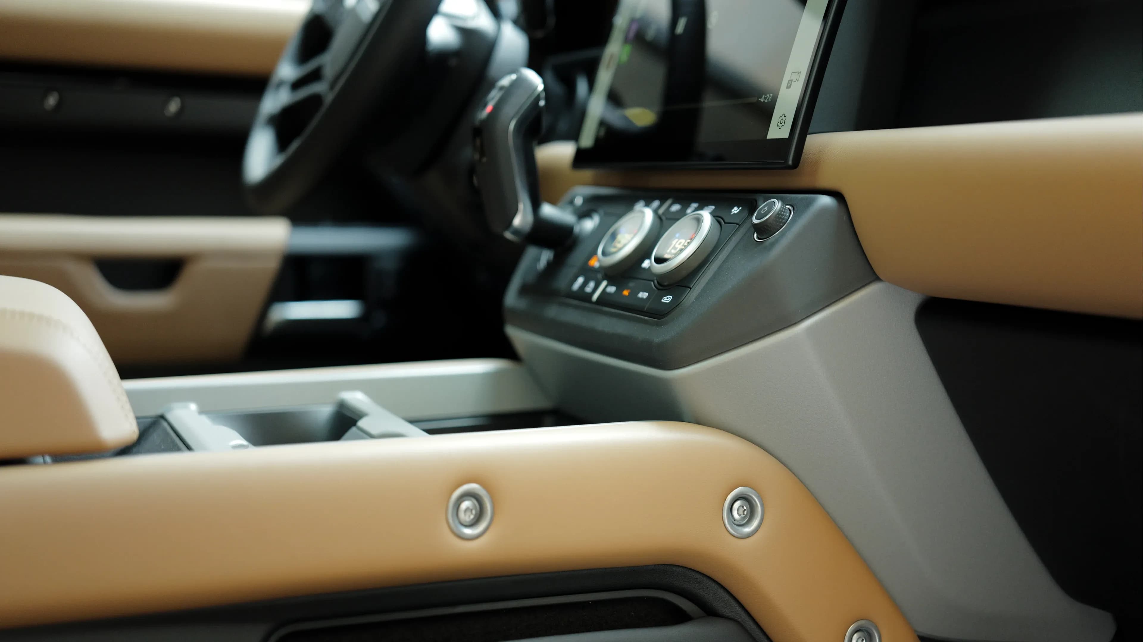 Land Rover Defender V8 mieten in München – Rustikale Schrauben-Details an der Mittelkonsole im robusten Luxus-Interieur von Mosaik Motors.