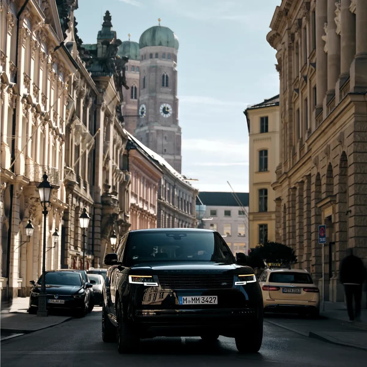 Range Rover mieten in München – Der Premium-SUV vor dem exklusiven Rosewood Hotel mit der ikonischen Frauenkirche im Hintergrund von Mosaik Motors.