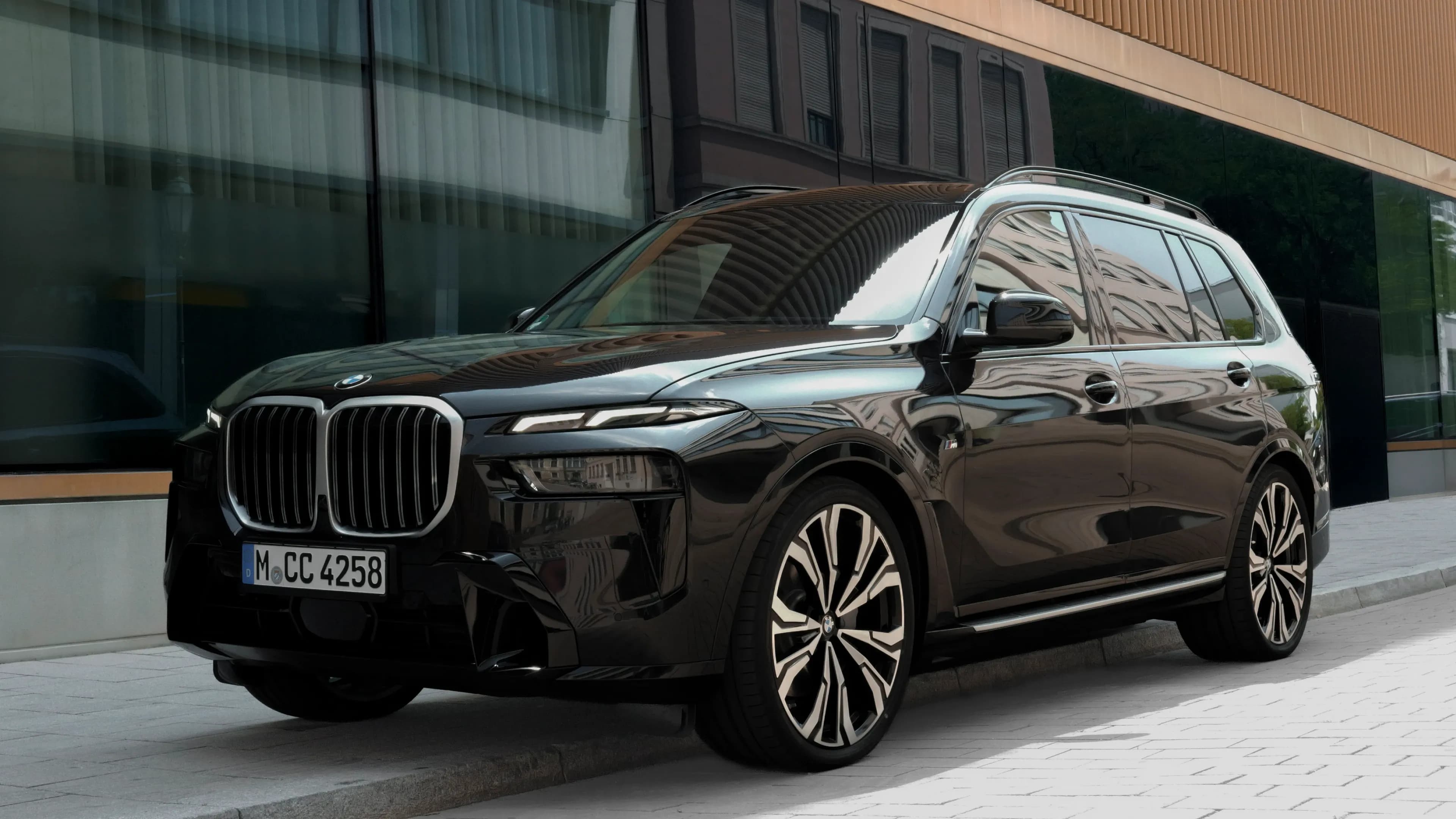 Schwarzer BMW X7 Luxus-SUV geparkt vor moderner Glasfassade des Lehnbachhaus in München.