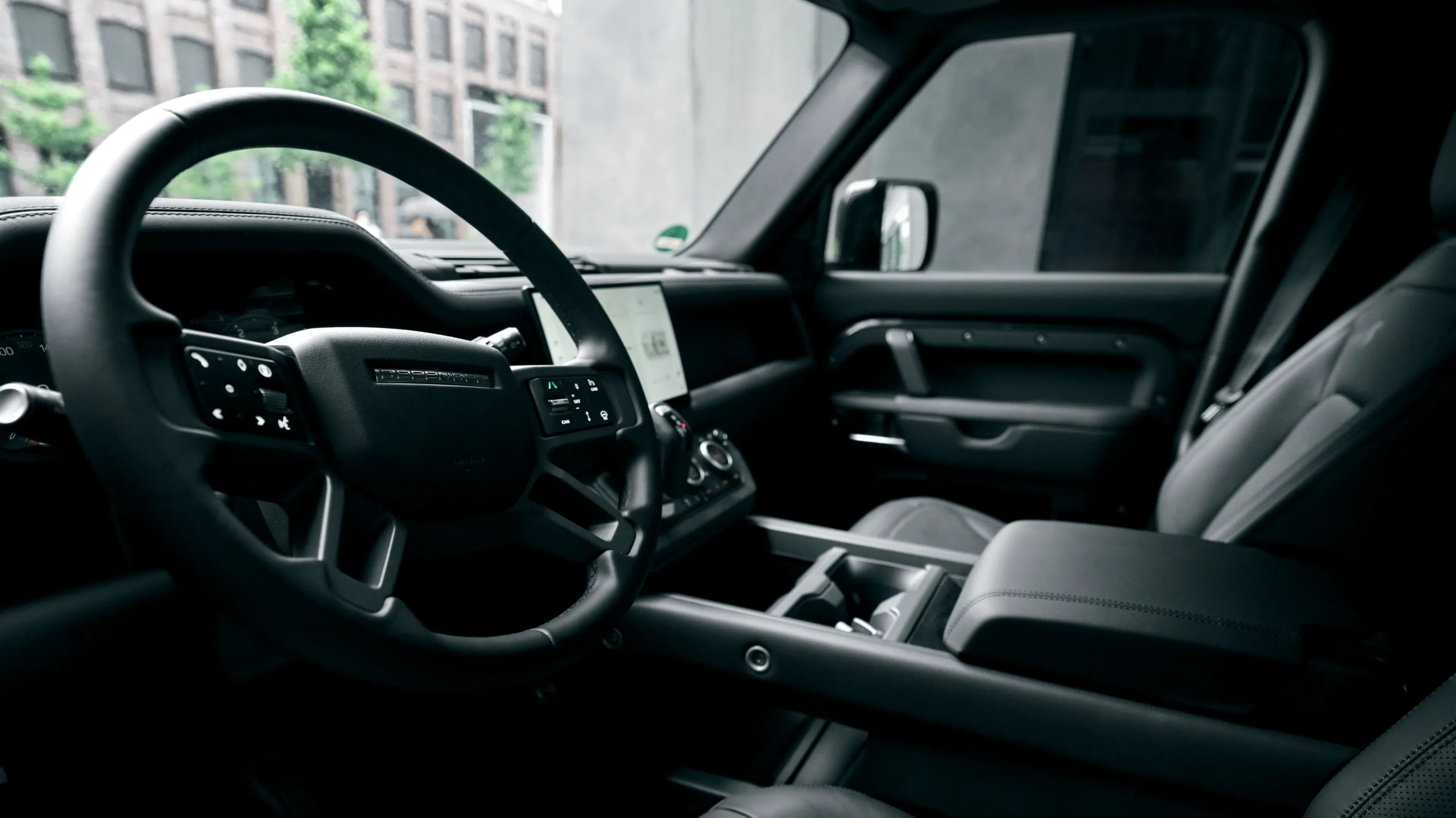 Cockpit eines Land Rover Defender mit Lenkrad und zentralem Touchscreen-Infotainment-System von Mosaik Motors.