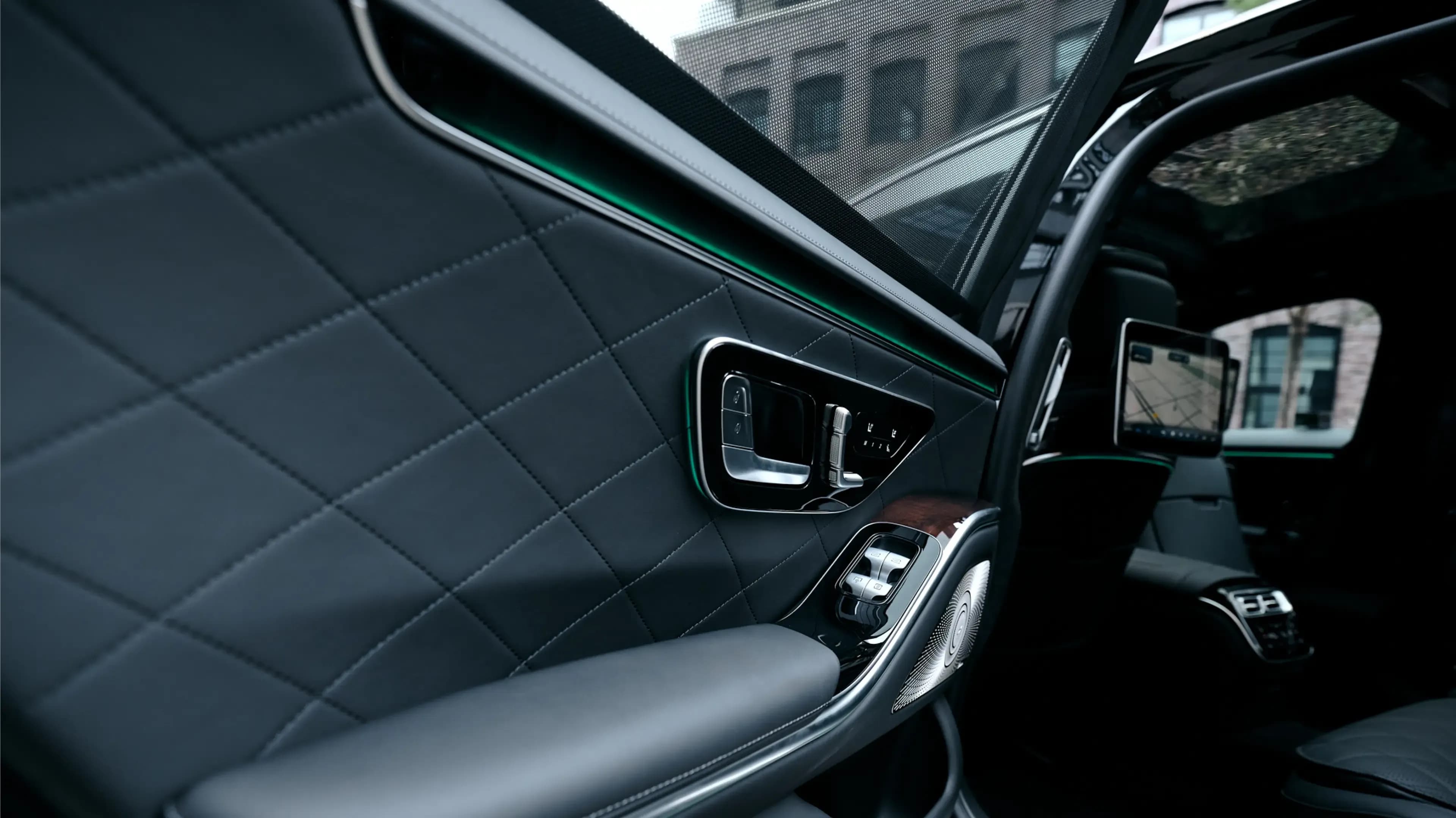 Mercedes-Benz S-Klasse mieten in München – Fond-Türverkleidung mit gestepptem Leder, grüner Ambientebeleuchtung und Sitzverstellung von Mosaik Motors.