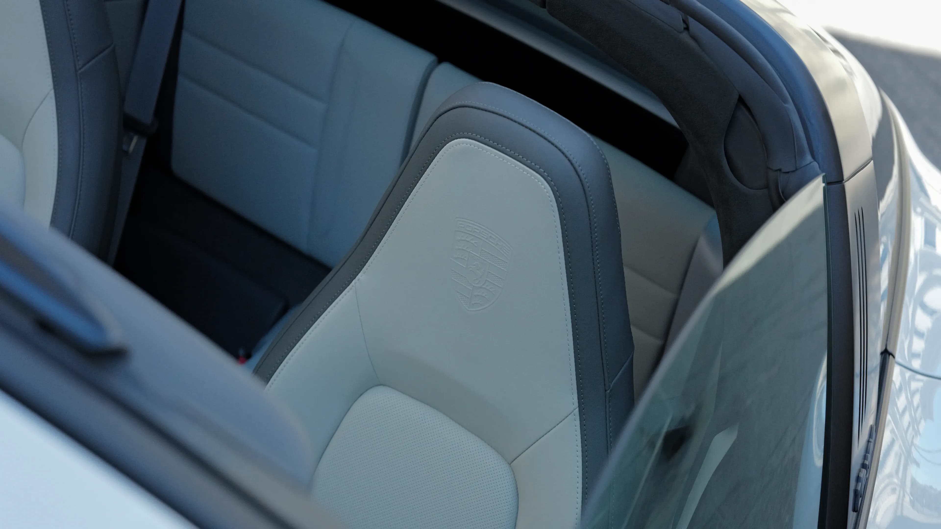 Premium leather sports seats with embossed Porsche crest inside the open Porsche Targa 4 GTS convertible.